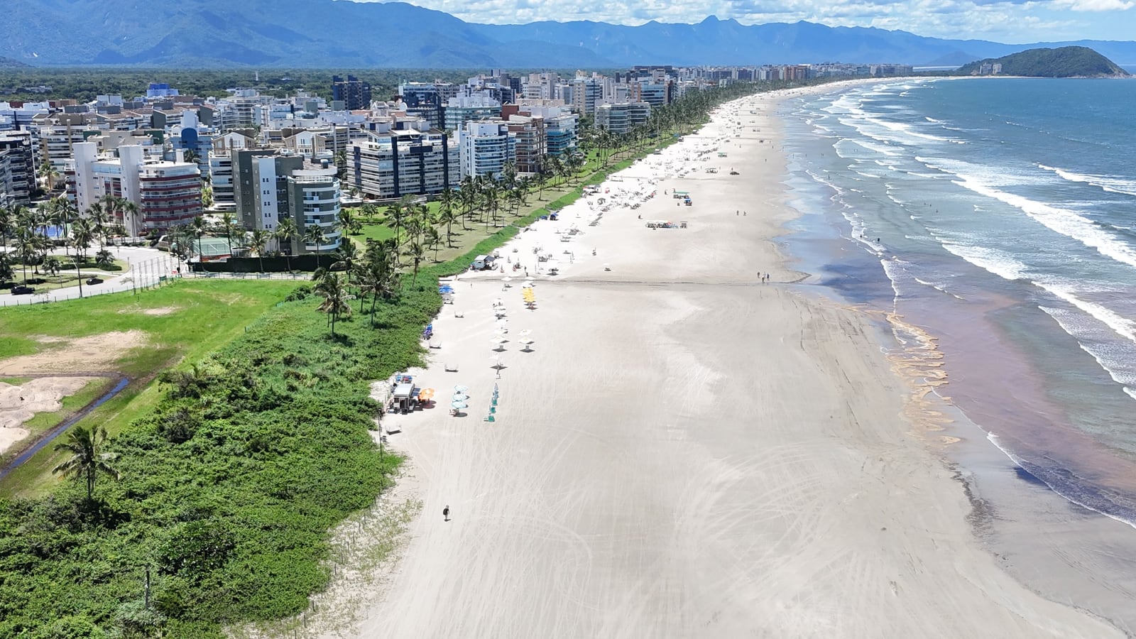 Praia da Riviera de São Lourenço com a restinga preservada, a faixa de areia e uma ilha no horizonte