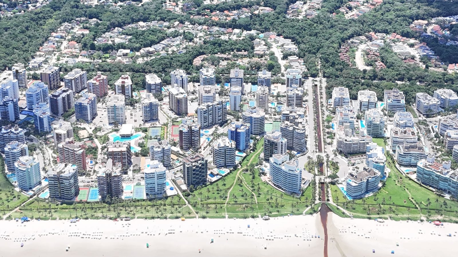 Casas e edifícios dos módulos da Riviera de São Lourenço vistos do alto, com a mata e a serra ao fundo