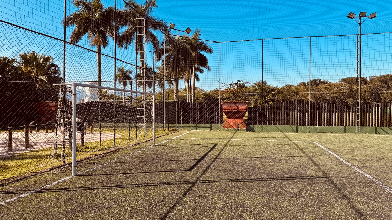 Campo de grama sintética com traves e palmeiras no Condomínio Hanga Roa