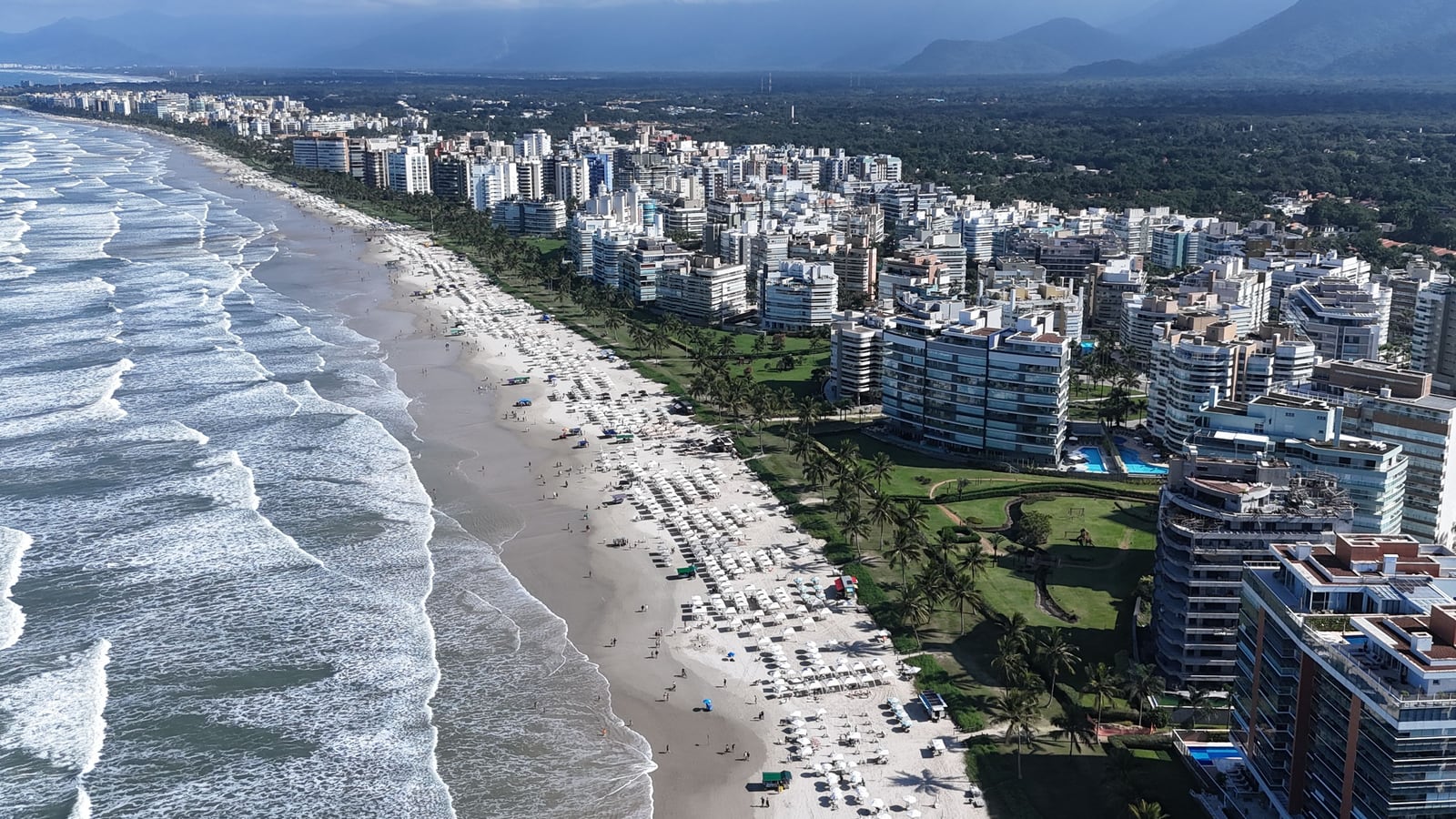 Praia movimentada da Riviera de São Lourenço com guarda-sóis e edifícios da orla, vista do alto