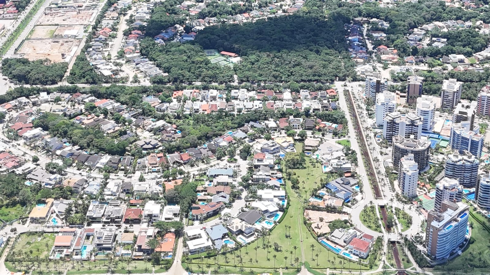 Avenida arborizada e módulos residenciais da Riviera de São Lourenço vistos do alto, com a praia em primeiro plano