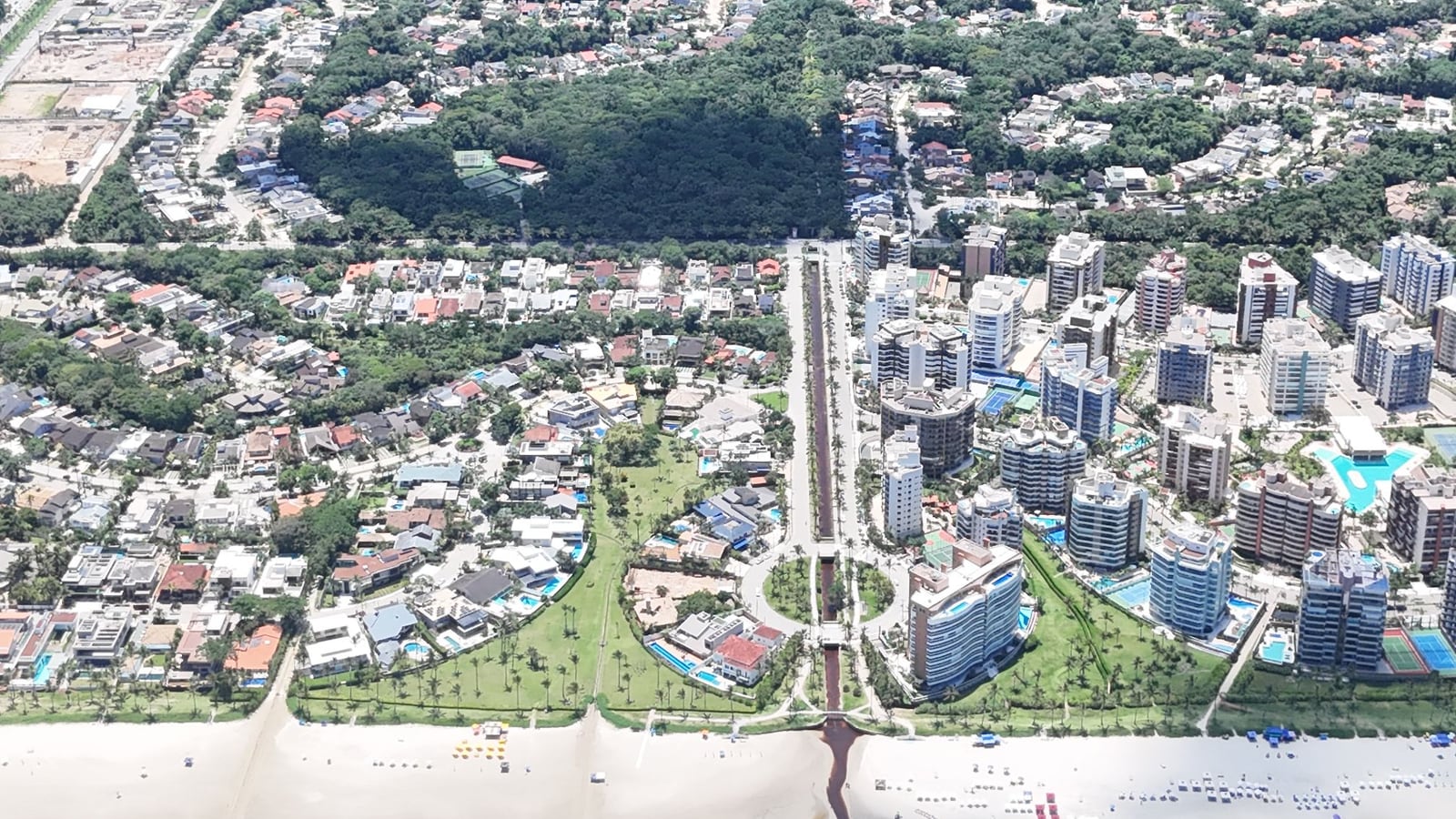 Vista aérea dos módulos da Riviera de São Lourenço, com a avenida, as casas, os edifícios e a mata ao fundo