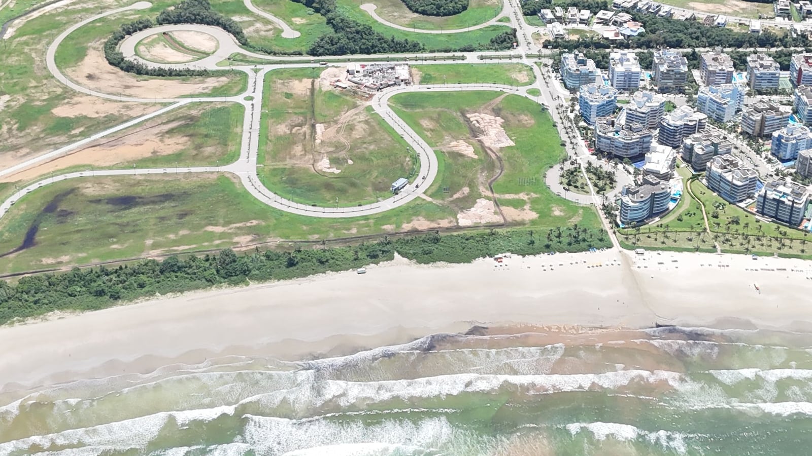 Módulos residenciais e áreas verdes da Riviera de São Lourenço vistos do alto, com a faixa de areia em primeiro plano