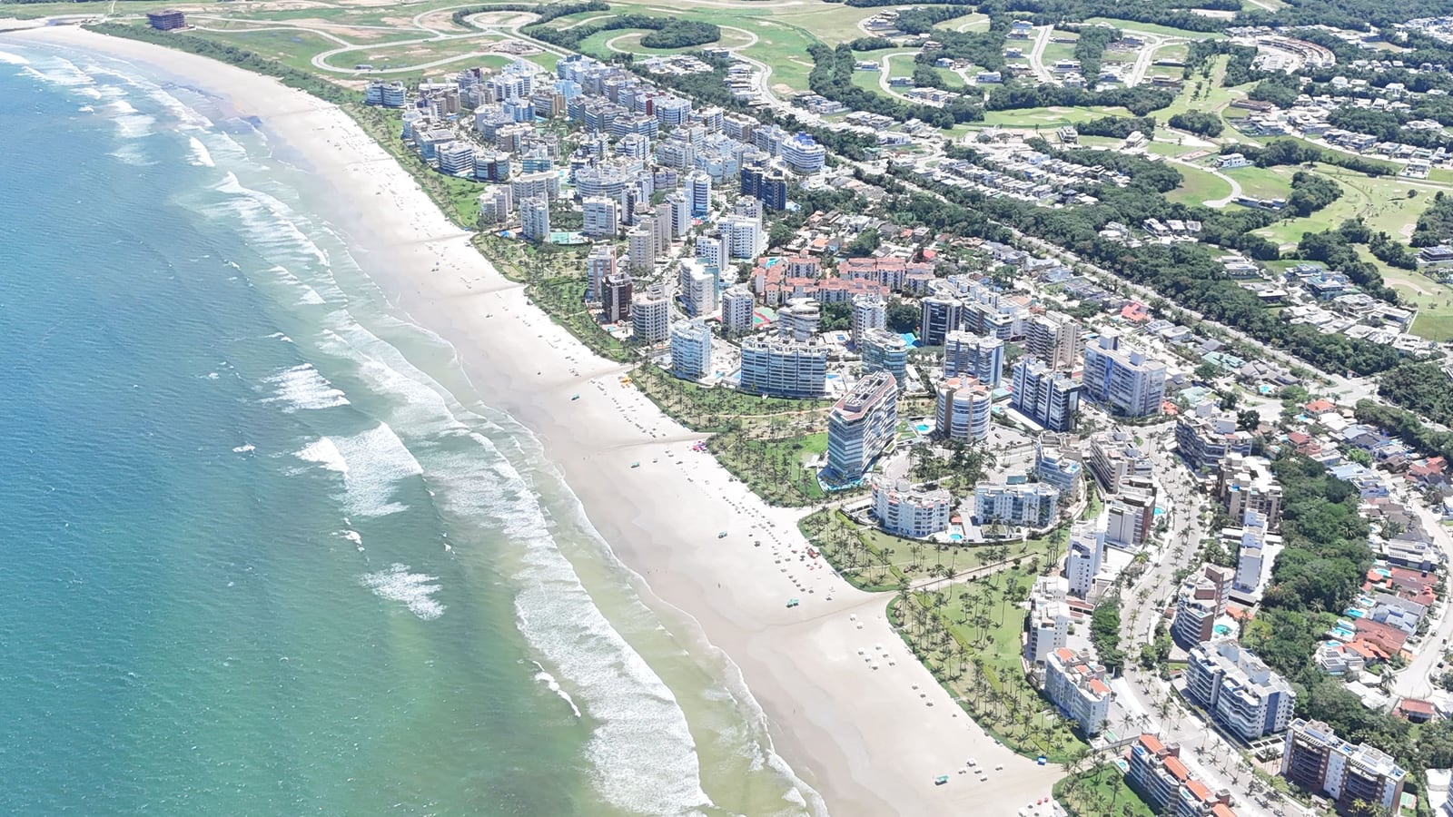 Mar azul, faixa de areia e módulos residenciais da Riviera de São Lourenço vistos do alto