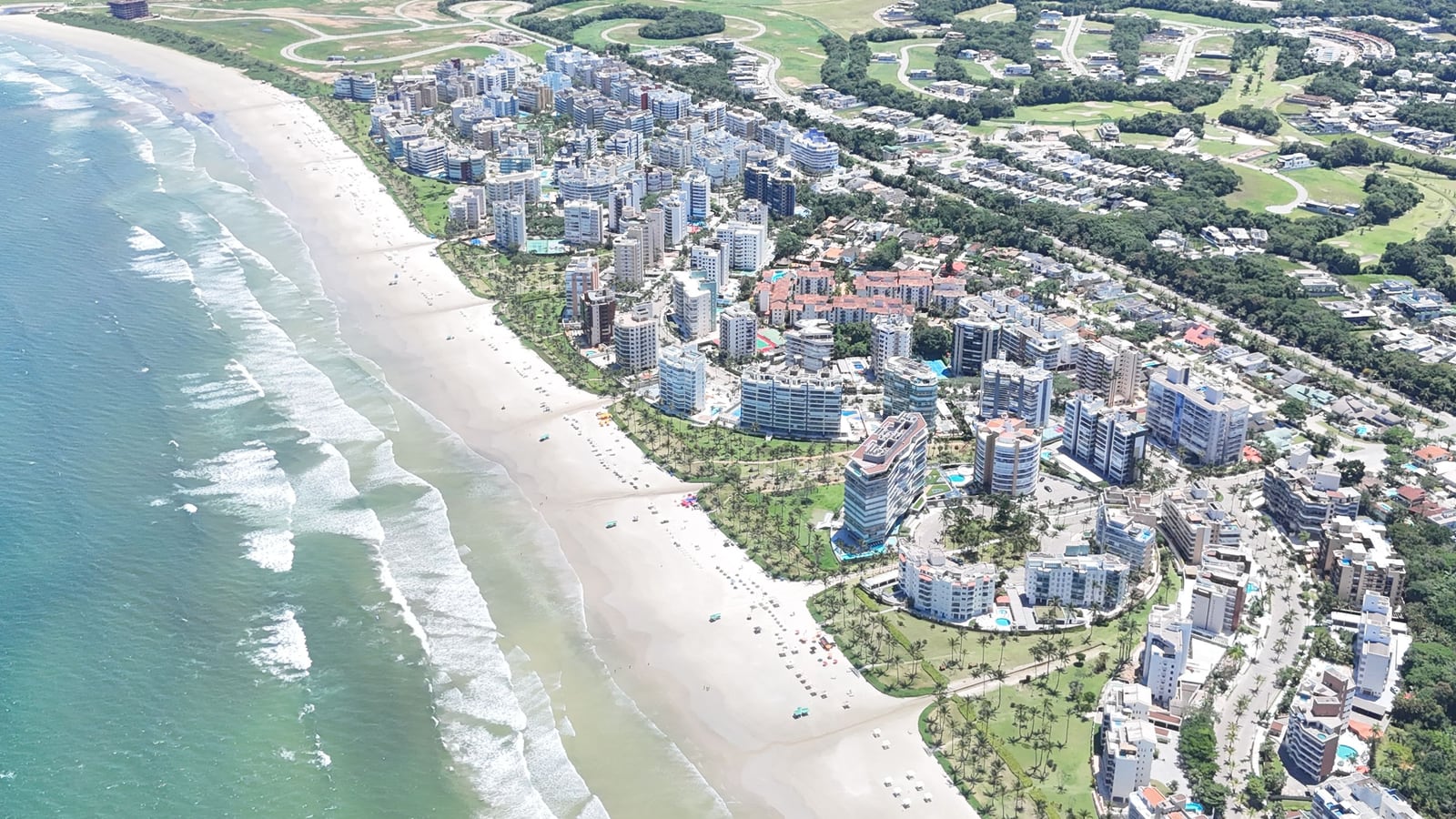 Orla da Riviera de São Lourenço vista do alto, com ondas, faixa de areia e os módulos à beira-mar