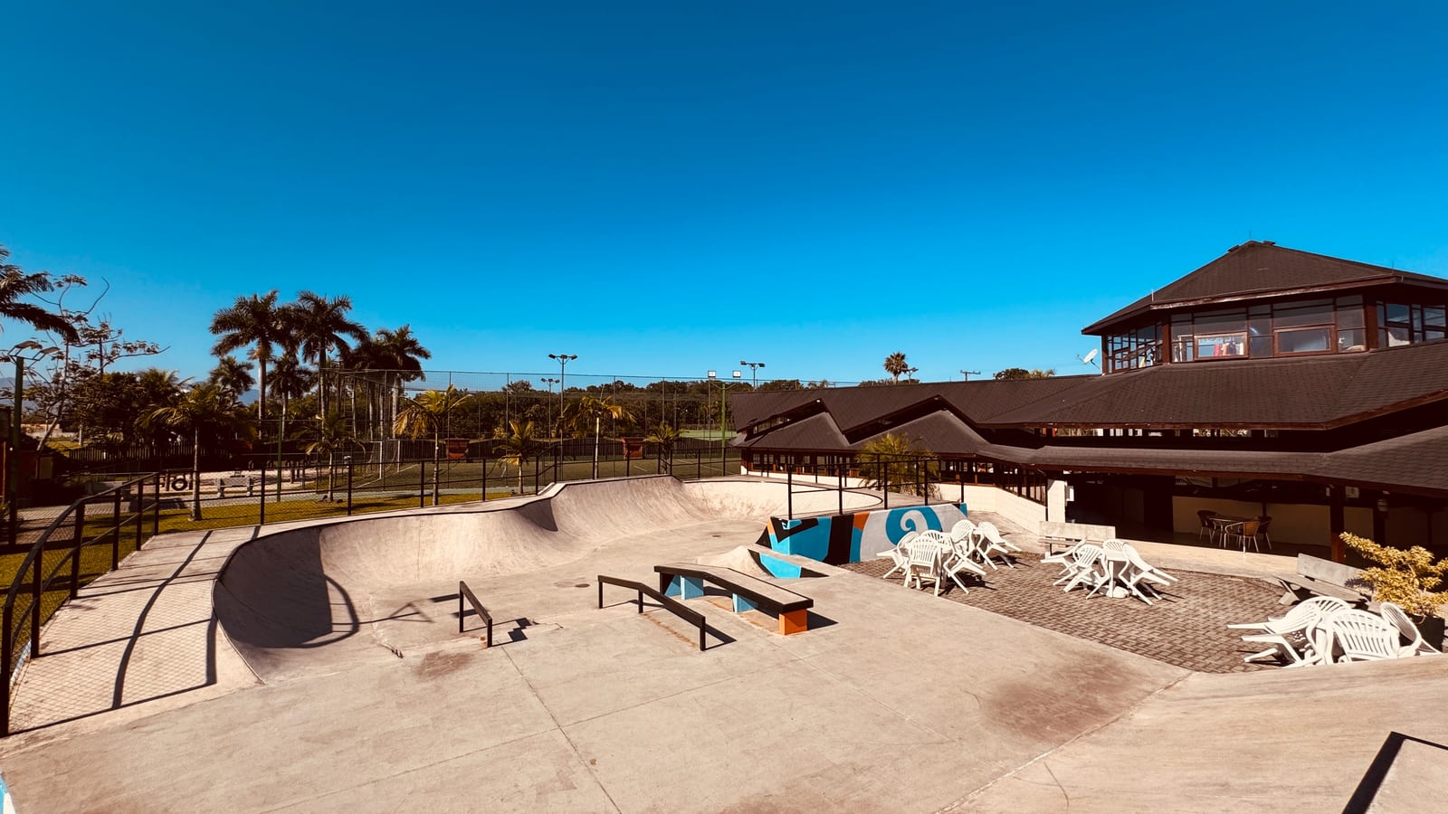 Pista de skate e área de convivência do Condomínio Hanga Roa, com palmeiras e o clube ao fundo