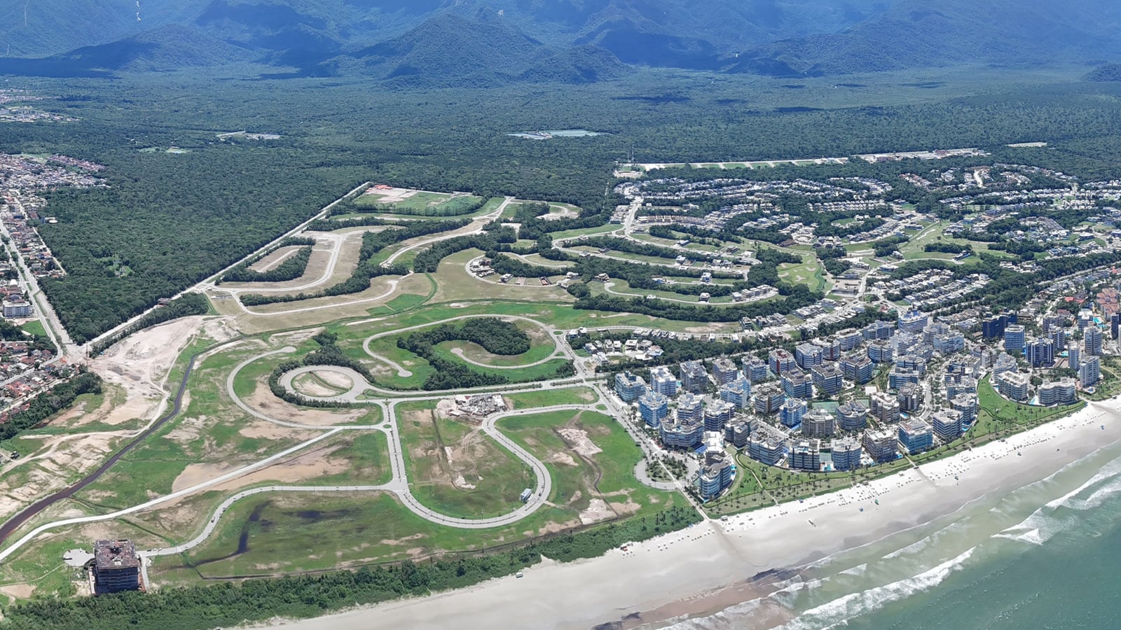 Litoral da Riviera de São Lourenço visto do alto, com a praia, os módulos residenciais, as áreas verdes e a serra